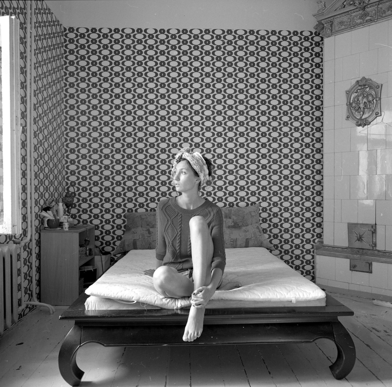 A seated figure within a patterned interior
